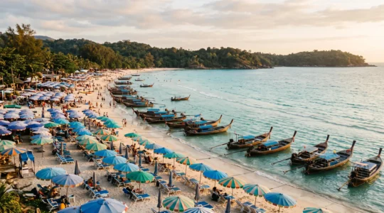 Vue symbolique d'une plage thailandaise partagee entre agitation touristique dense et horizon calme et preserve